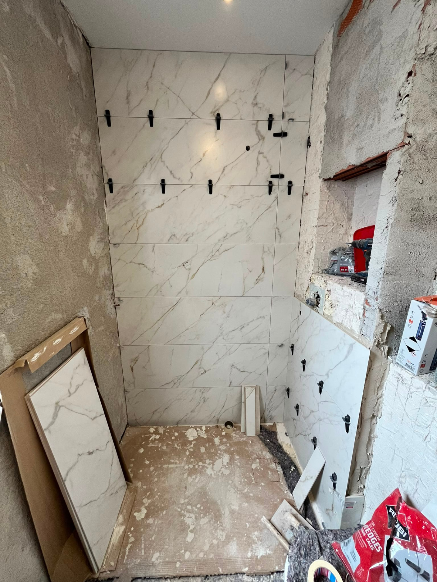 Colocación de gres porcelánico en la ducha durante la reforma de baño en Valencia