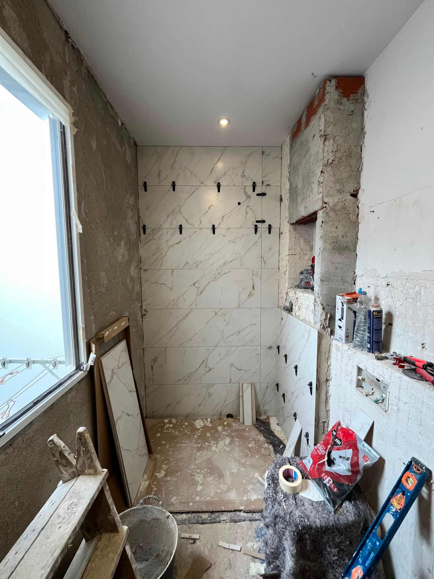 Alicatado del plato de ducha con porcelánico efecto mármol en una reforma de baño en Valencia