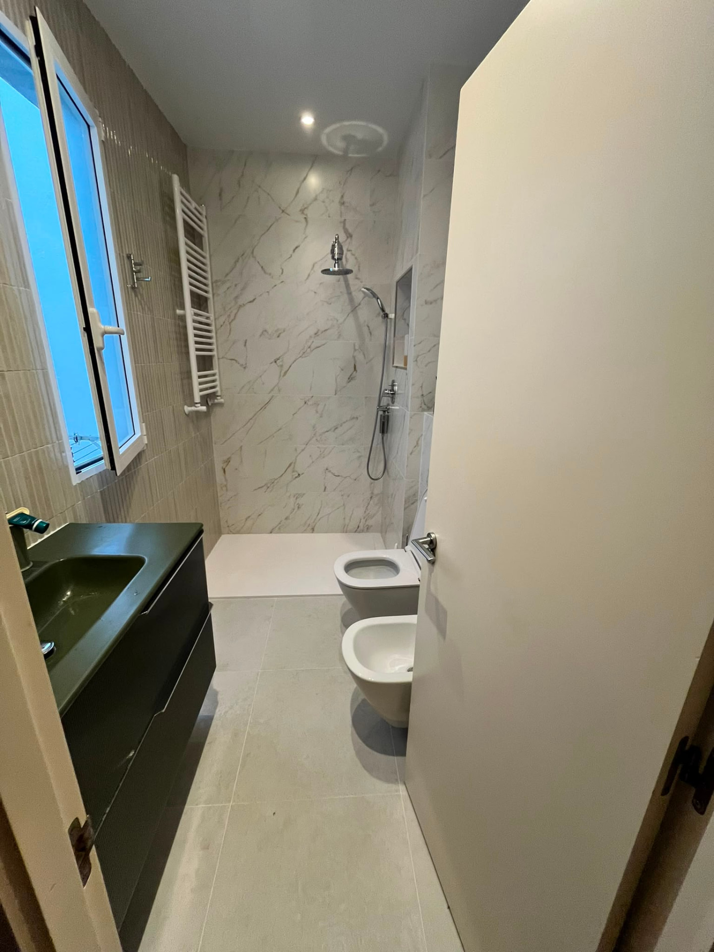 Baño terminado en Valencia con mueble suspendido verde y ducha nueva